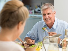 An older man eating a salad with his wife