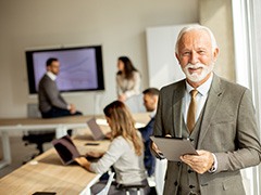 A senior businessman working on a digital tablet in a conference room