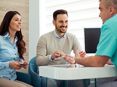 Dentist and couple talking in dental office