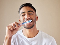 Man smiling while brushing his teeth